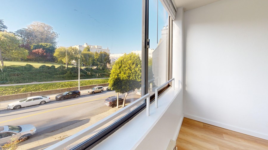 A view from a window looking out at a street with cars and trees.